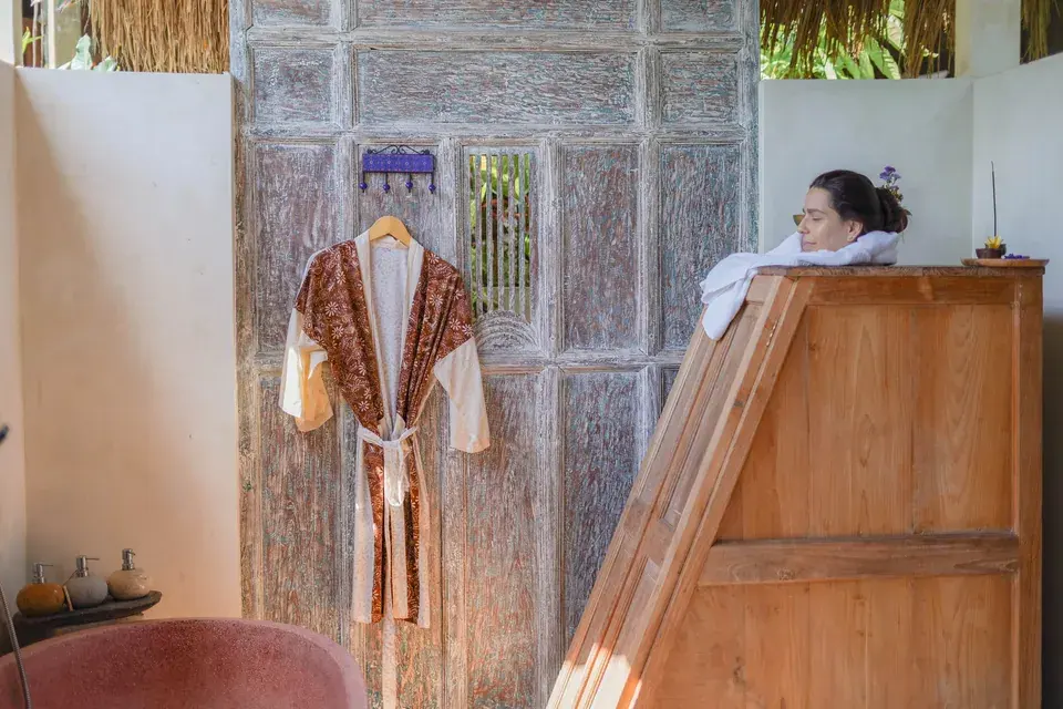 A guest seated in the wooden herbal steam box