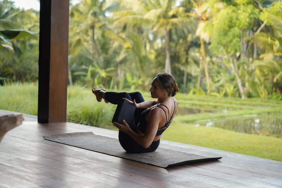A guest practising a seated balance pose with a yoga block
