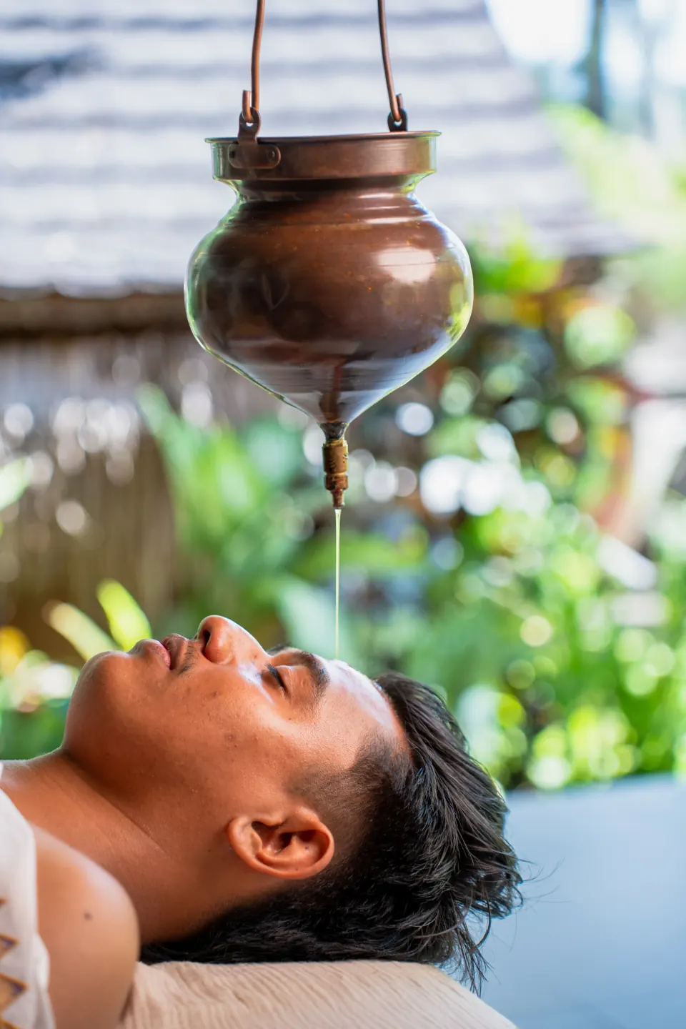 A male guest receiving a Shirodhara oil treatment at the spa