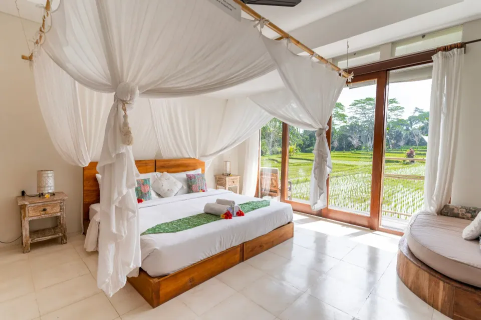 A canopy bed beside windows overlooking the garden