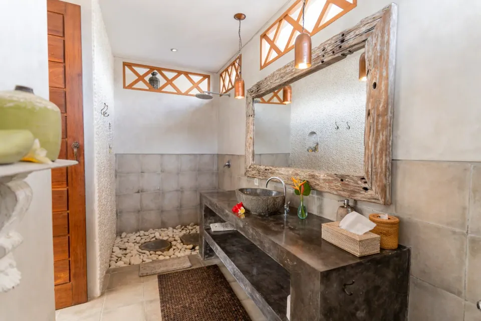 A tiled bathroom with a wooden counter and large mirror